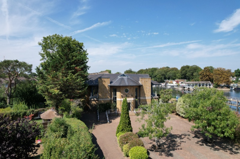 Front-facing drone view of property with formal gardens