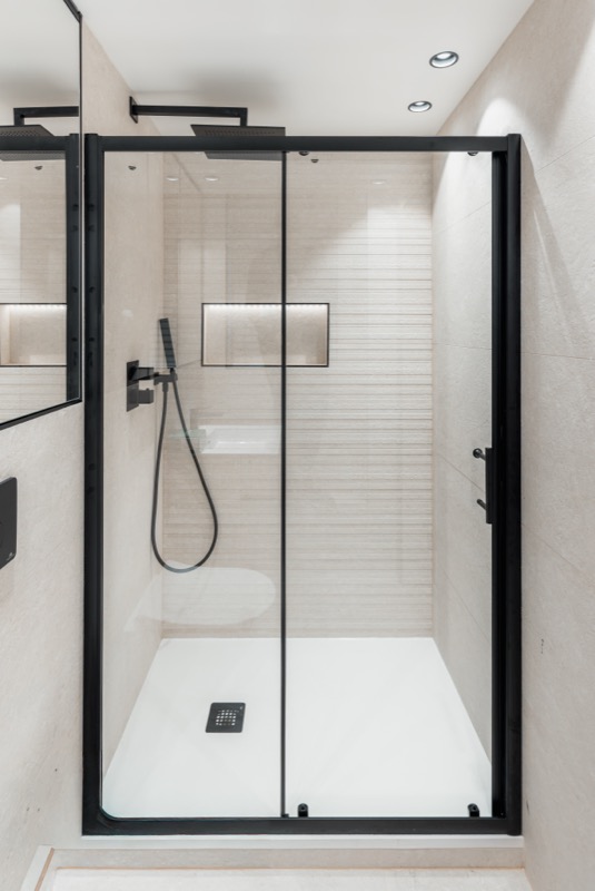 Contemporary shower enclosure with black frame and beige tiles