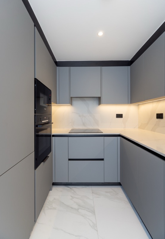 Sleek grey kitchen with marble backsplash and built-in appliances